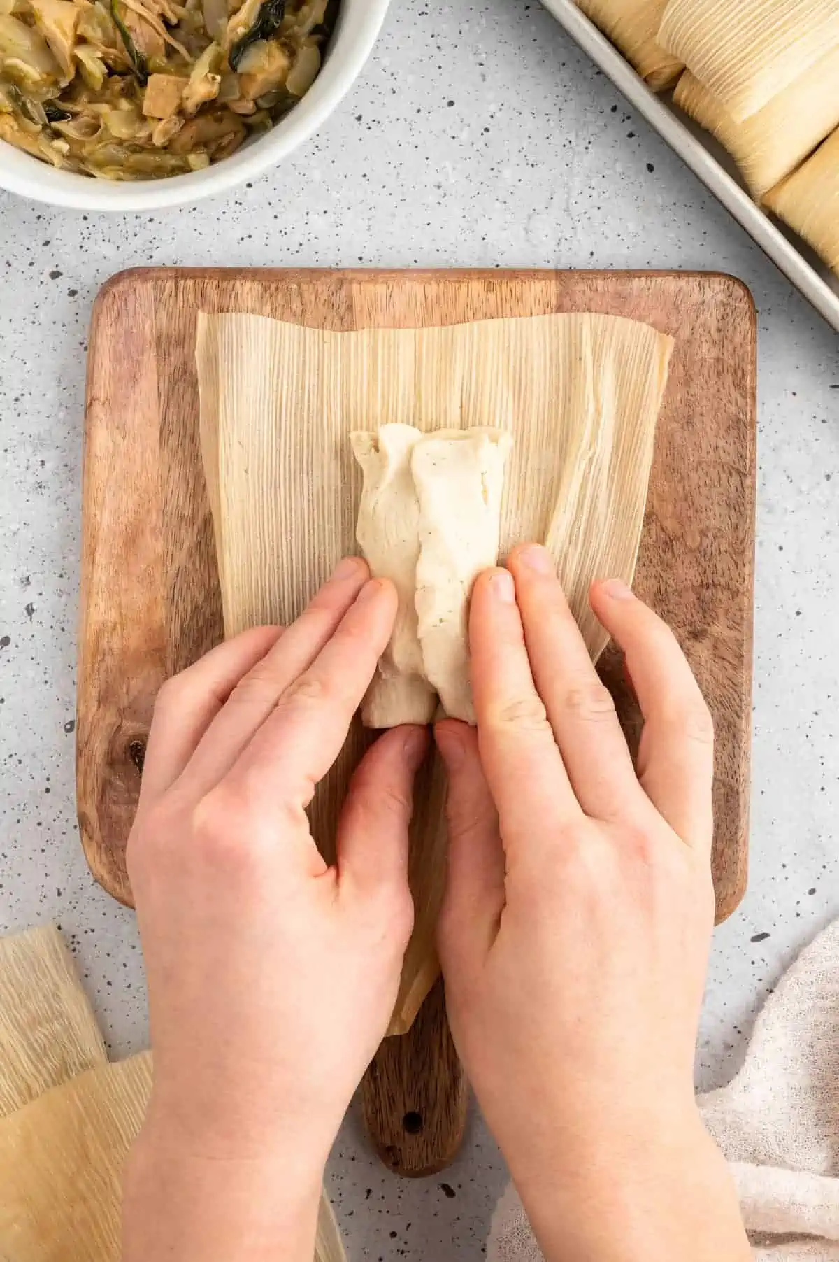 Hands assembling a vegan tamale.