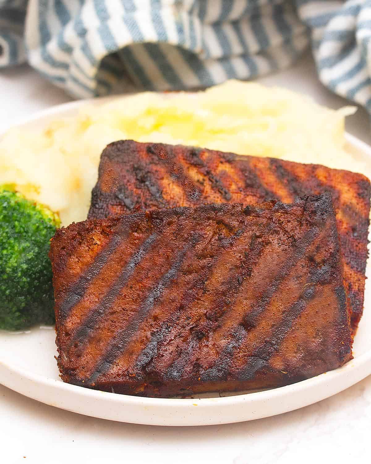 Two grilled tofu steaks on a plate.