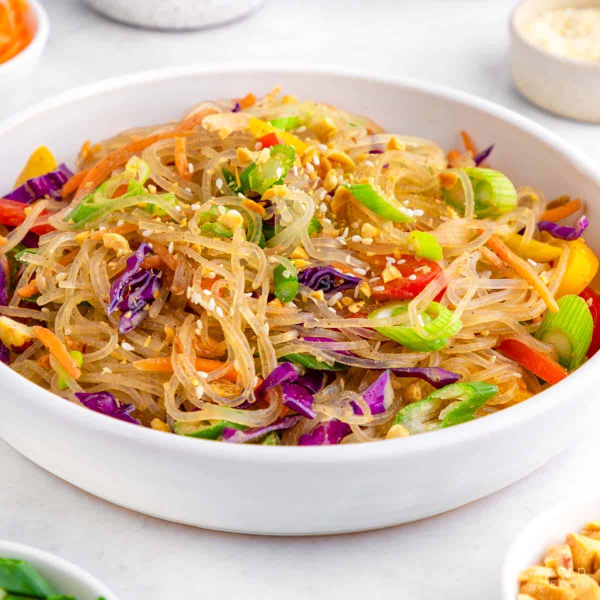 Glass kelp noodles salad with rainbow veggies served in a white bowl.