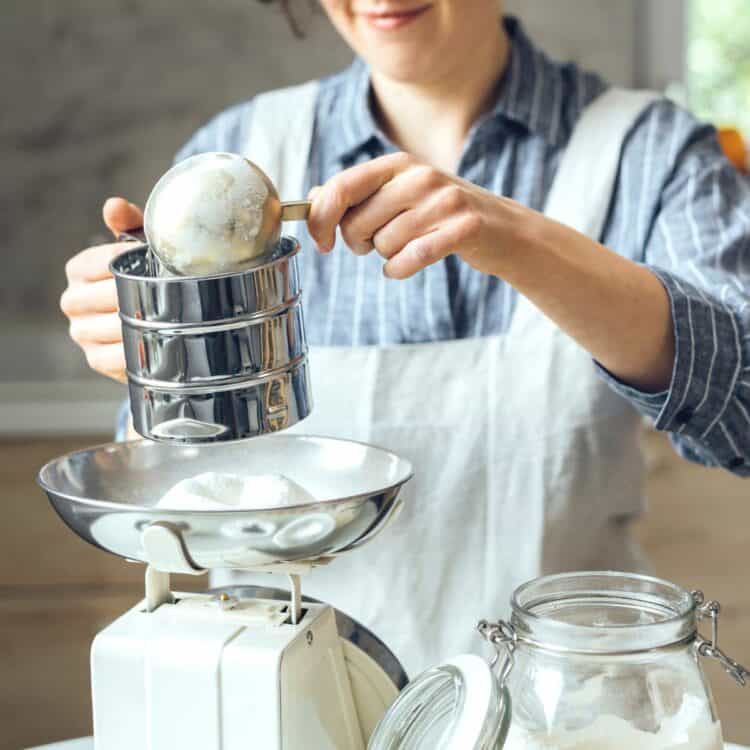 Baker measuring flour by weight to determine grams in an ounce.