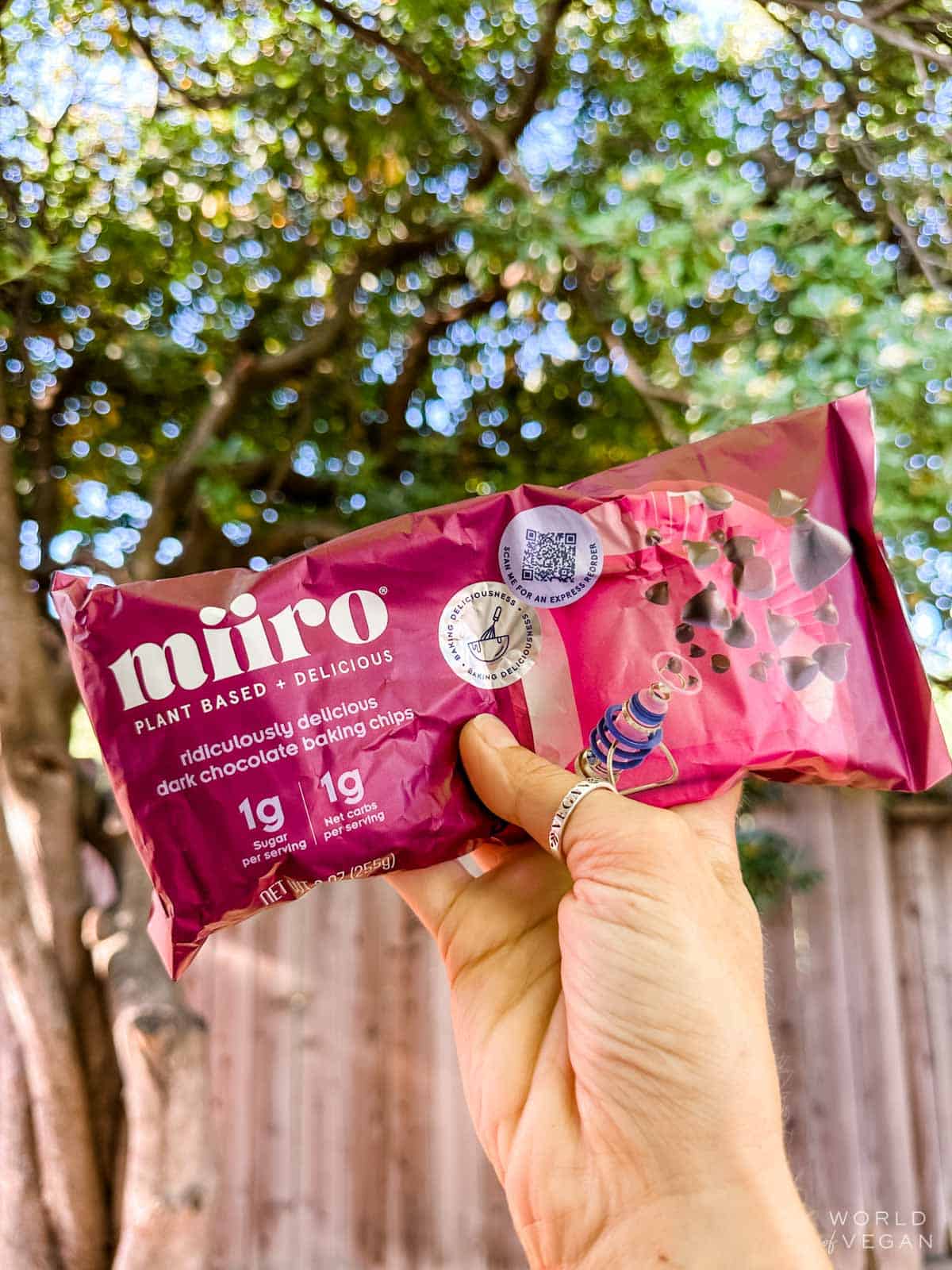 A hand holding up a bag of miiro vegan dark chocolate baking chips.