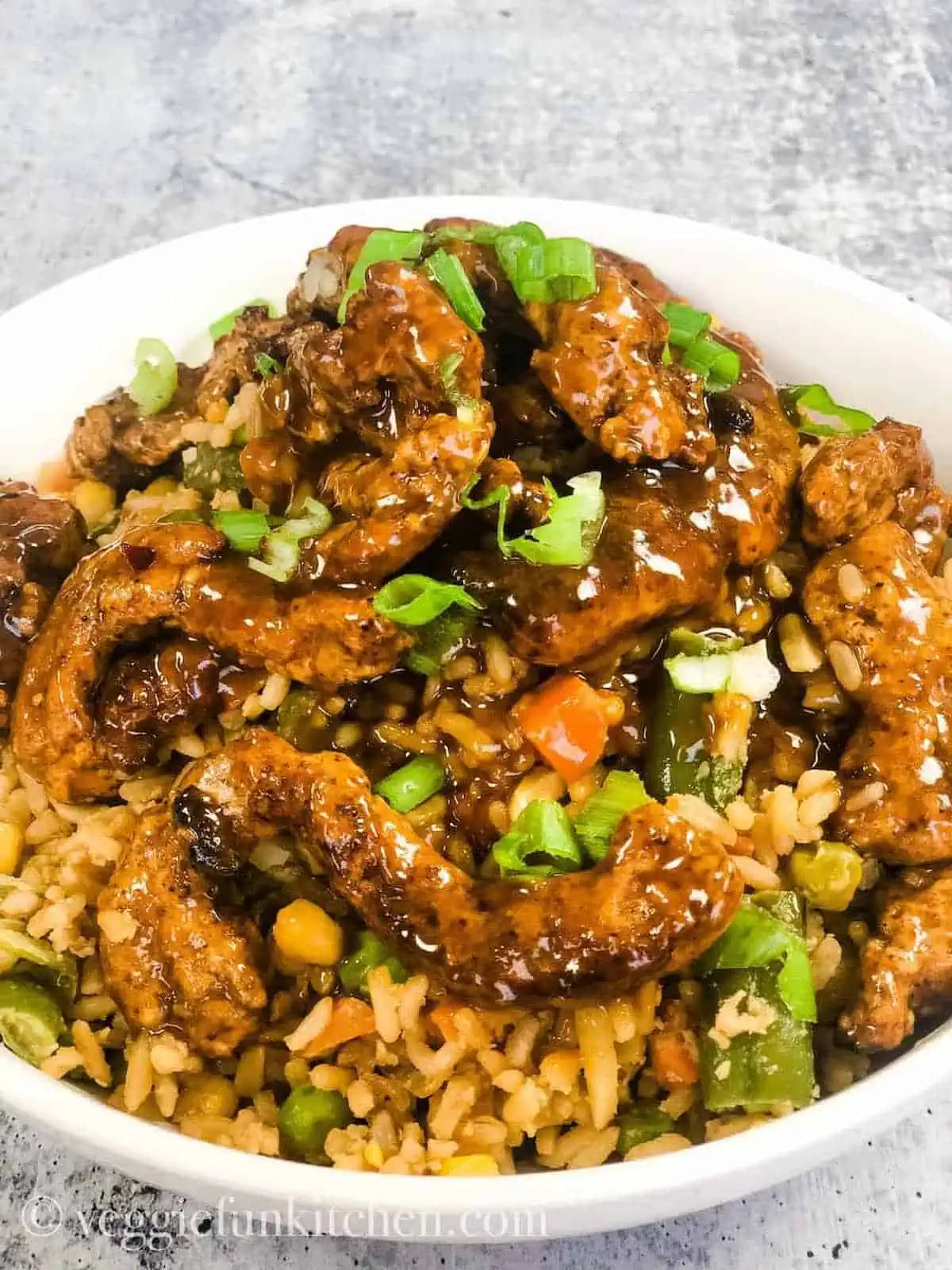 A bowl of vegan orange chicken served over fried rice.