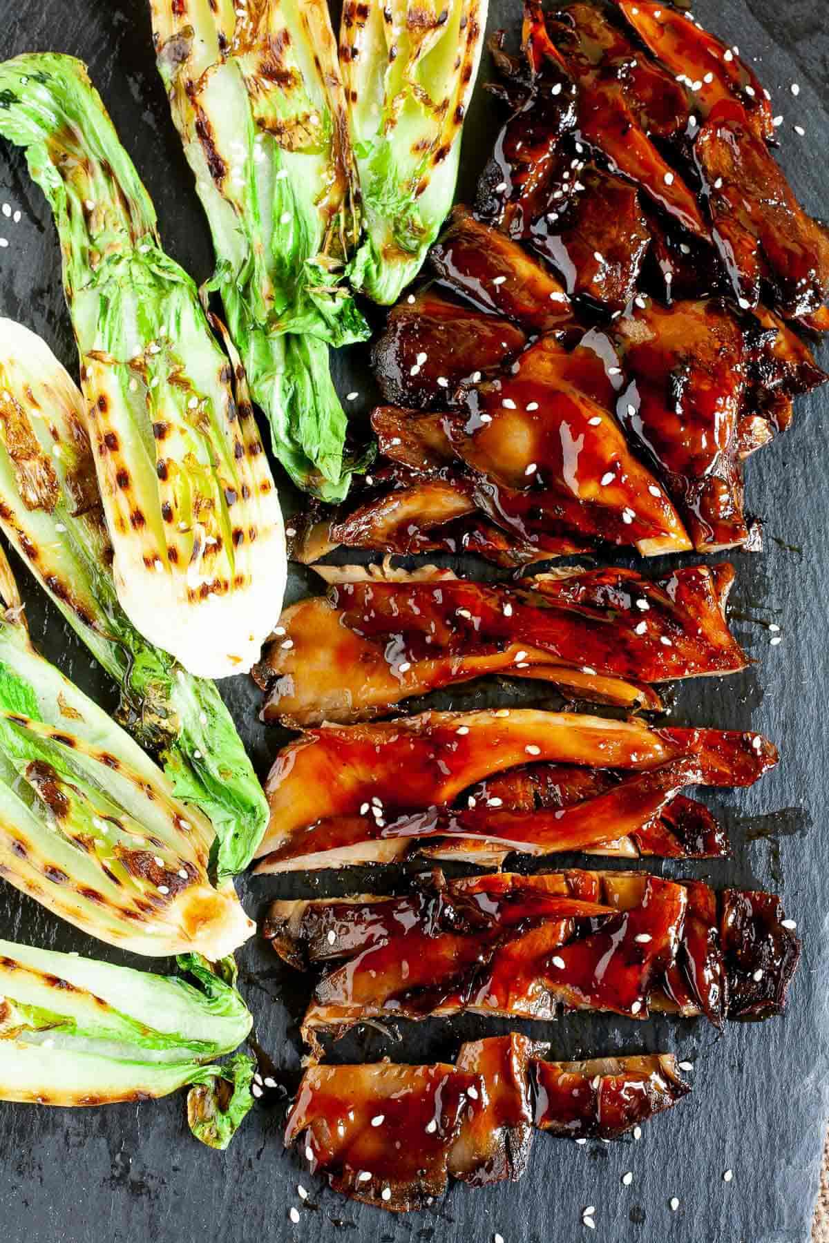 Grilled oyster mushroom steak on a plate with grilled bok choy.