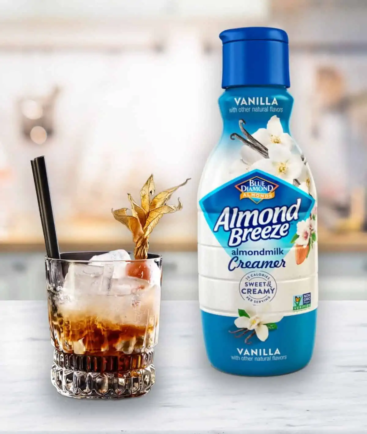 Bottle of Almond Breeze Vanilla almondmilk creamer next to a glass of iced espresso.