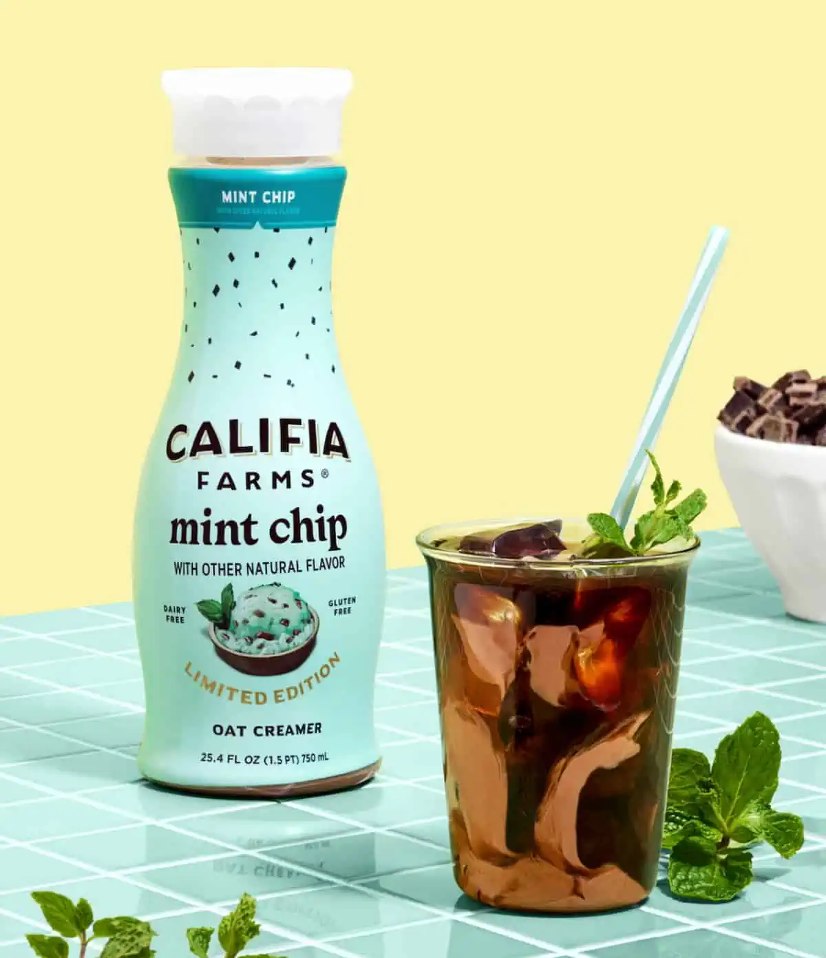 Oat-based Mint Chip coffee creamer from Califia Farms next to a mint chocolate coffee drink with mint leaves.