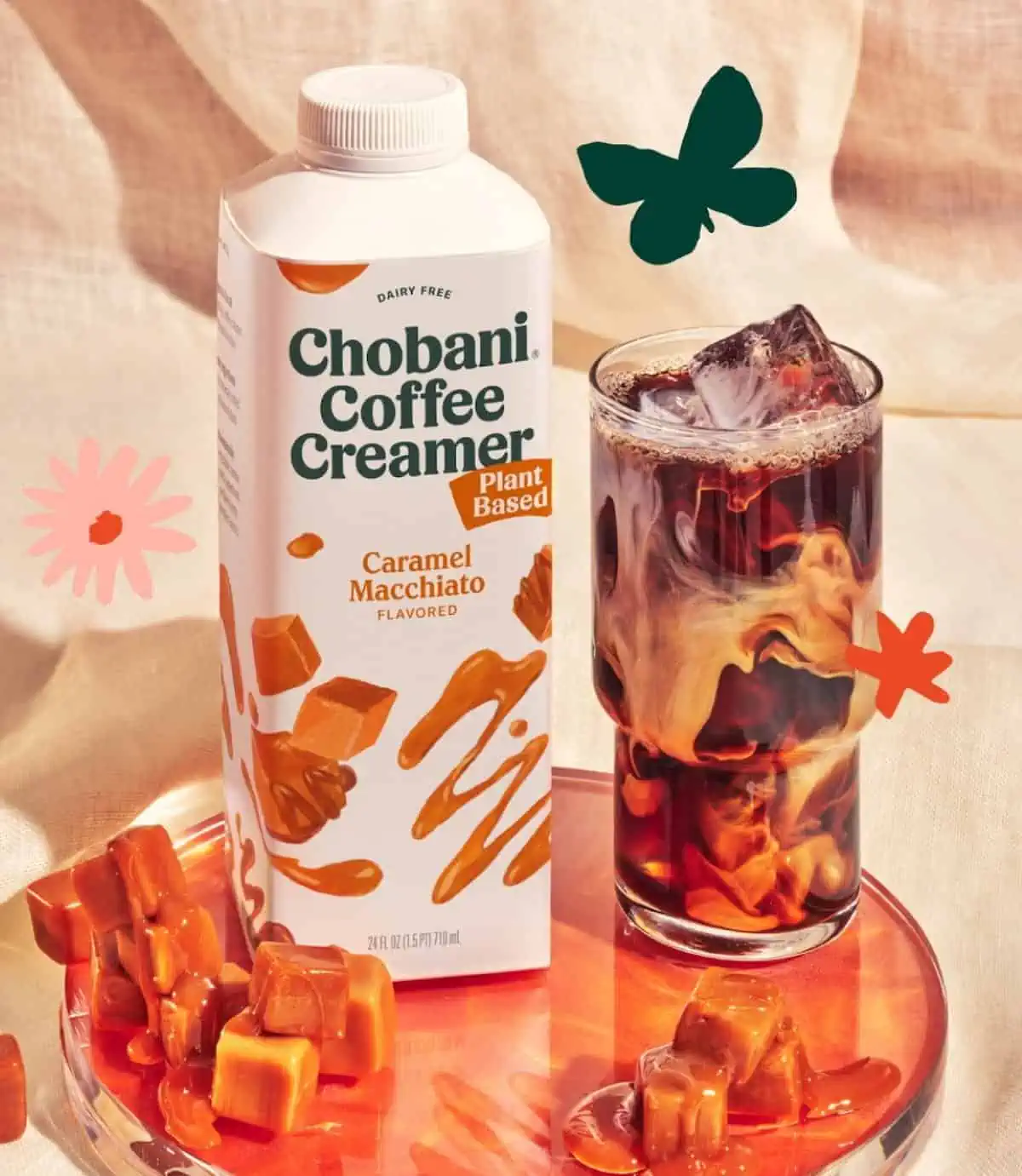 Carton of Chobani plant-based coffee creamer in Caramel Macchiato flavor next to a caramel macchiato in a glass.