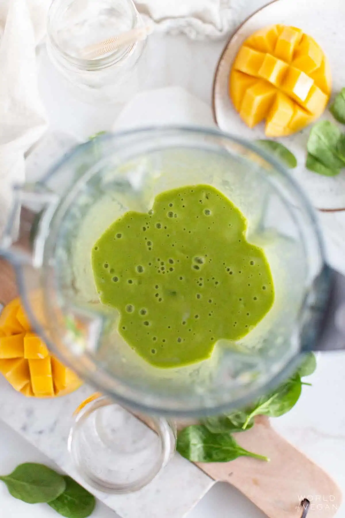 A mango spinach smoothie in a blender.