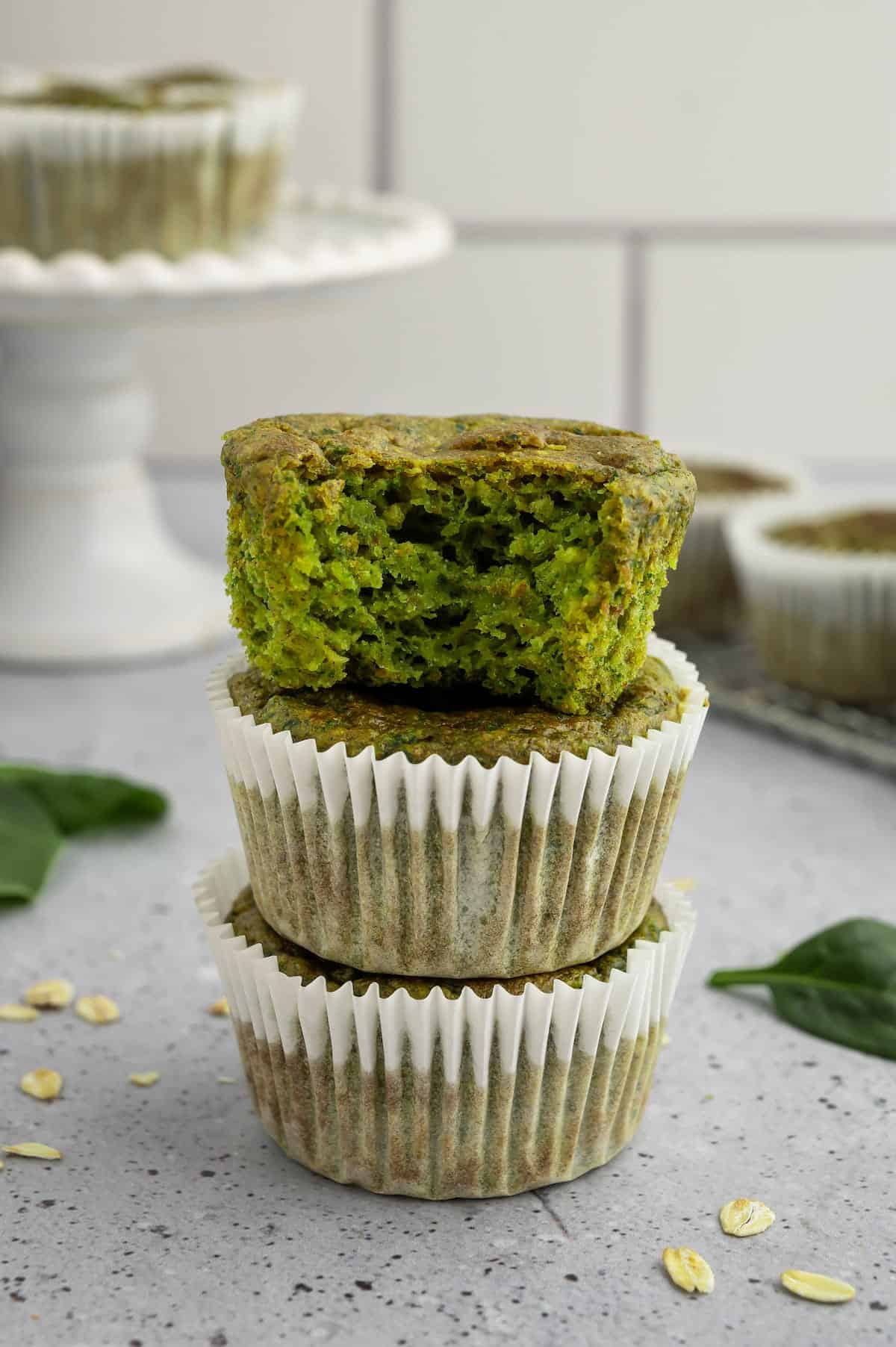 Spinach banana muffins stacked on a countertop.