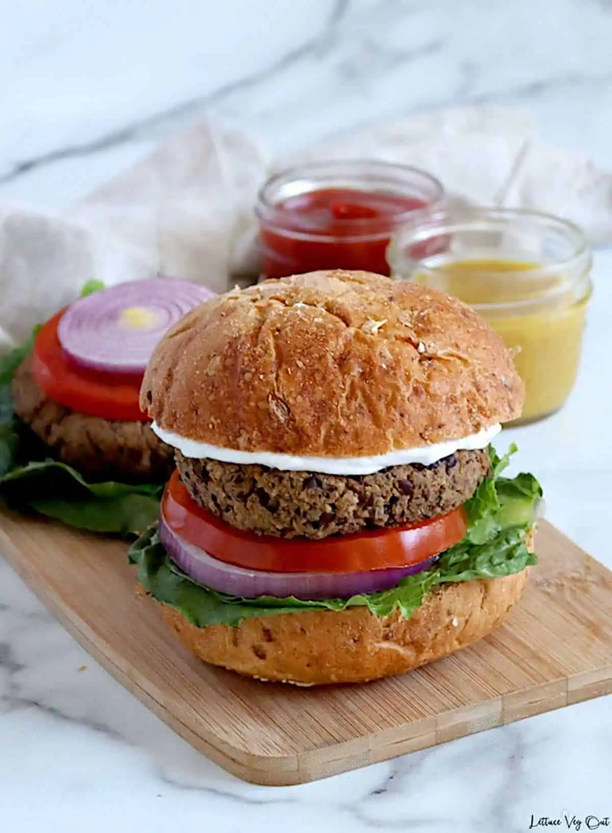 A whole food plant-based burger with toppings served in a whole wheat bun.