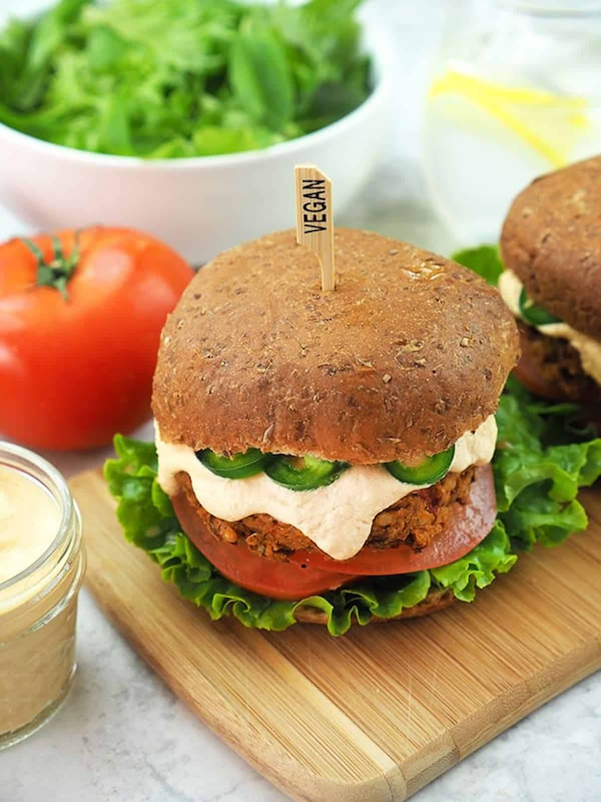 Chipotle lentil burger in a bun with vegan cheese sauce dripping out the sides.