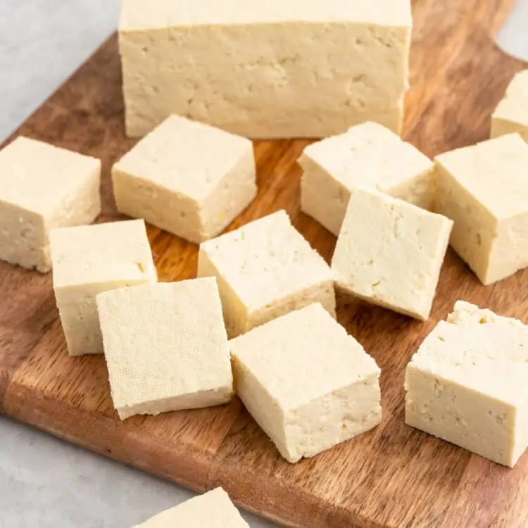 Cubed raw tofu on a cutting board.