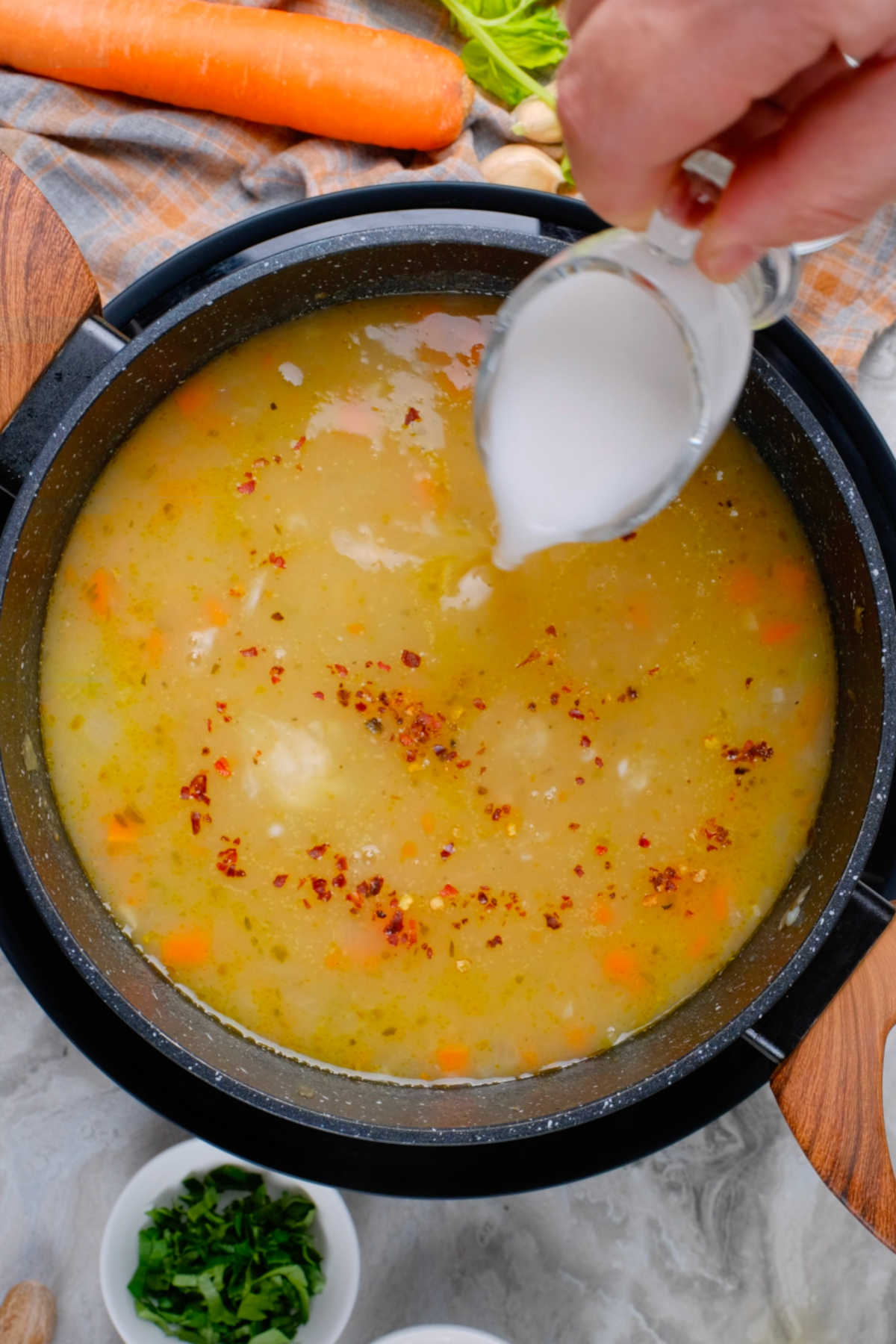 Dairy-free cream being poured into the vegan potato soup.