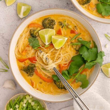 Overhead shot of Thai vermicelli noodle soup with rice noodles, vegetables, and fresh herbs.