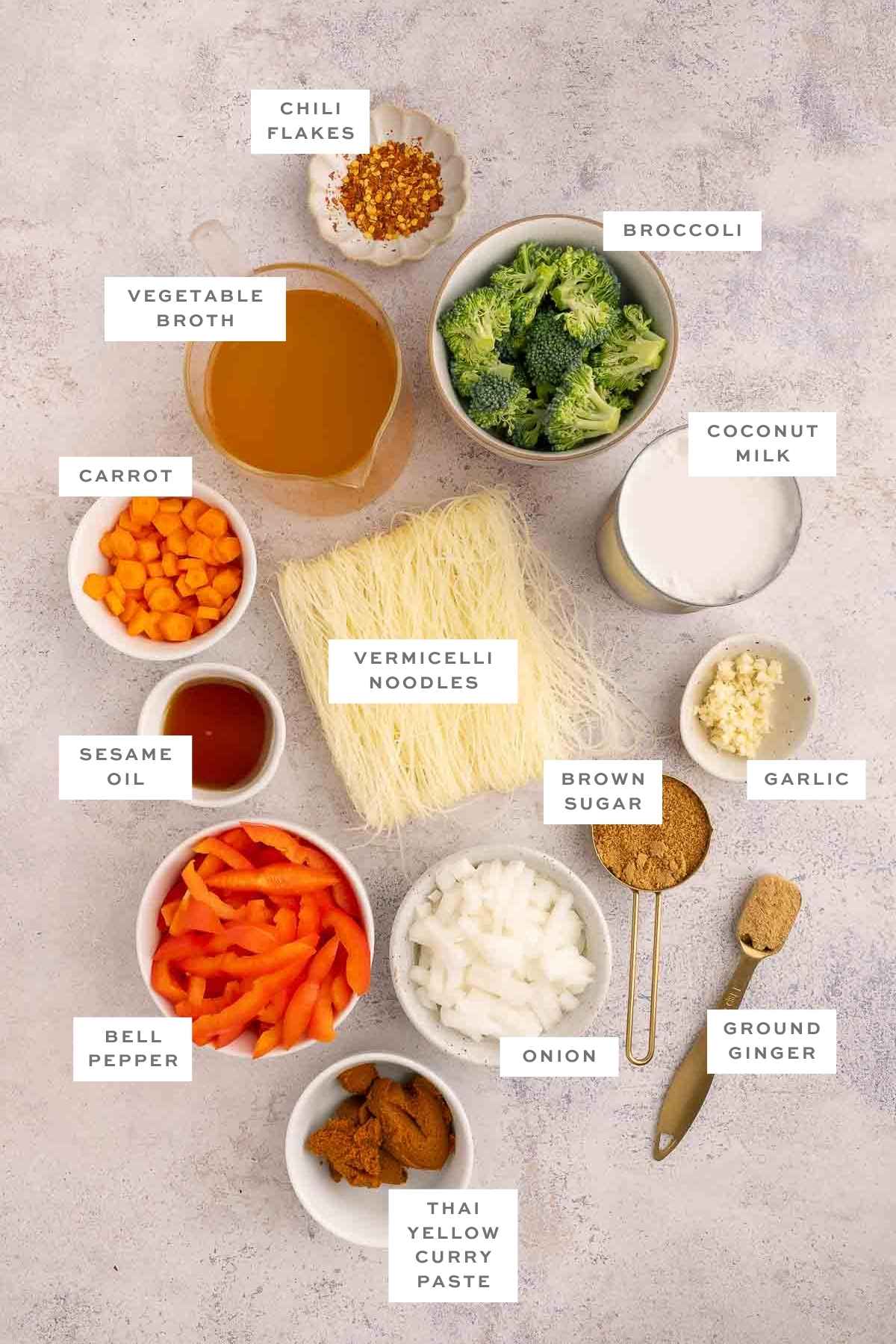 Flat lay of key ingredients for vermicelli noodle soup including rice noodles, broth, and vegetables.