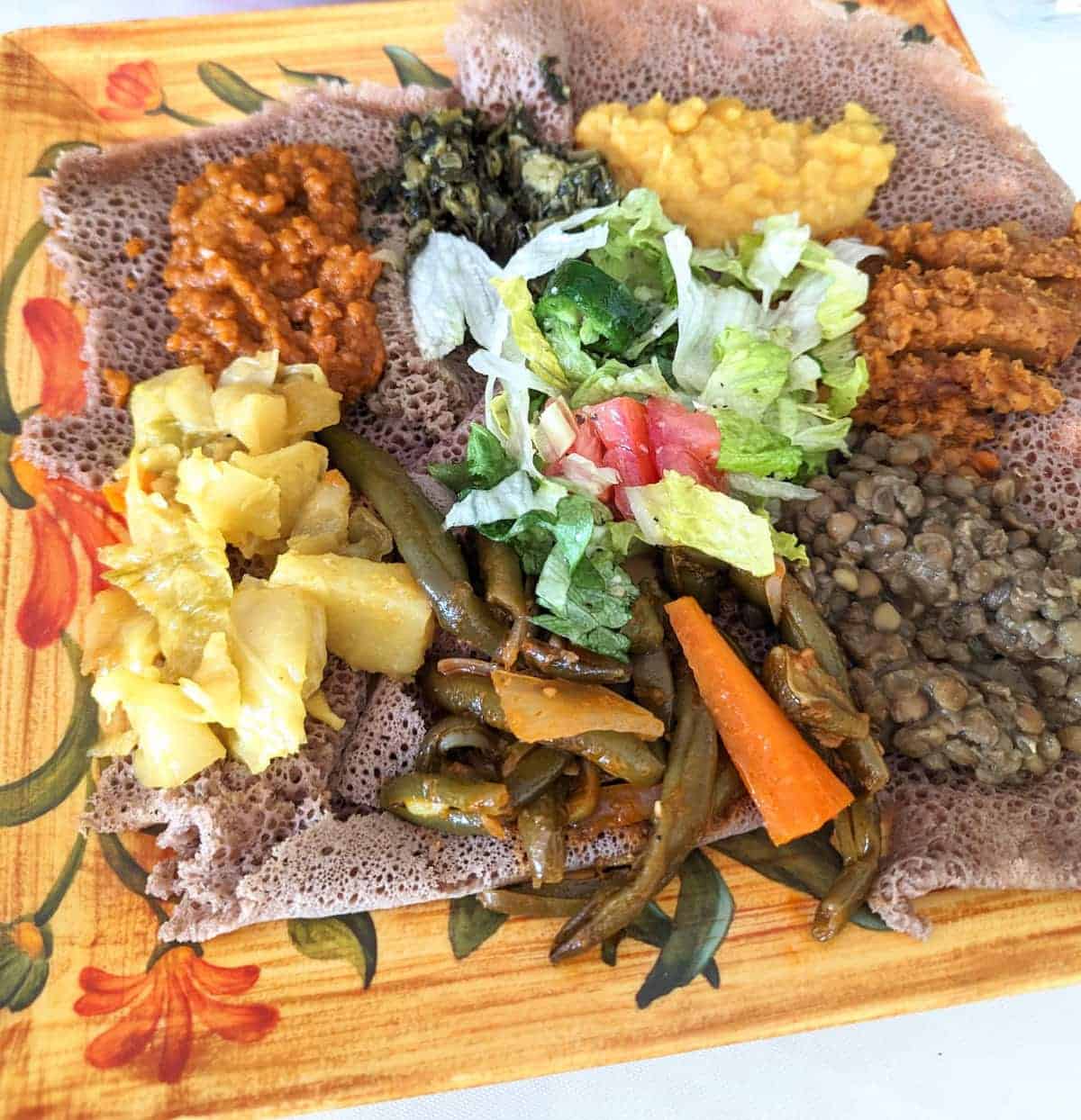 Veggie platter with various vegetarian Ethiopian dishes served over Injera flatbread.