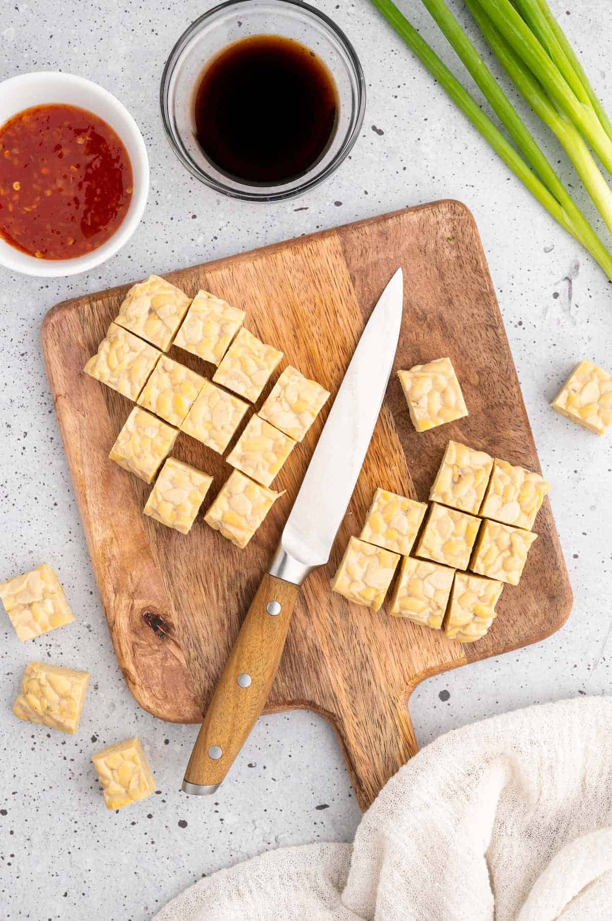 Cubed tempeh on a cutting board.