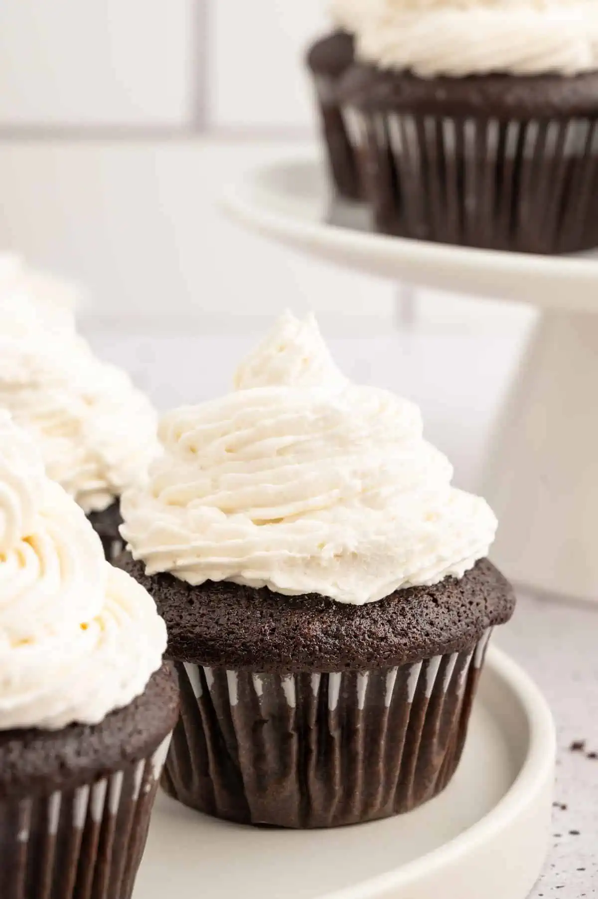 Vegan cupcakes on a plate, topped with vegan buttercream frosting.