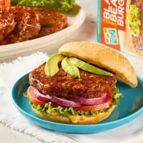 Don Lee Farm's Black Bean Burger on a bun topped with sliced avocado.
