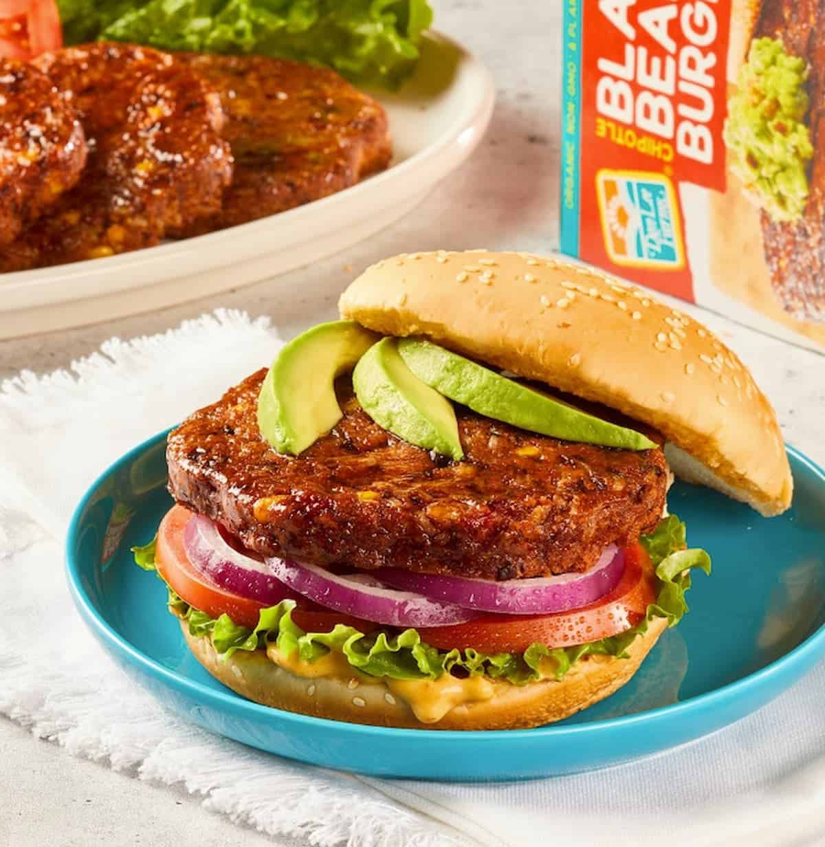 Don Lee Farm's Black Bean Burger on a bun topped with sliced avocado.