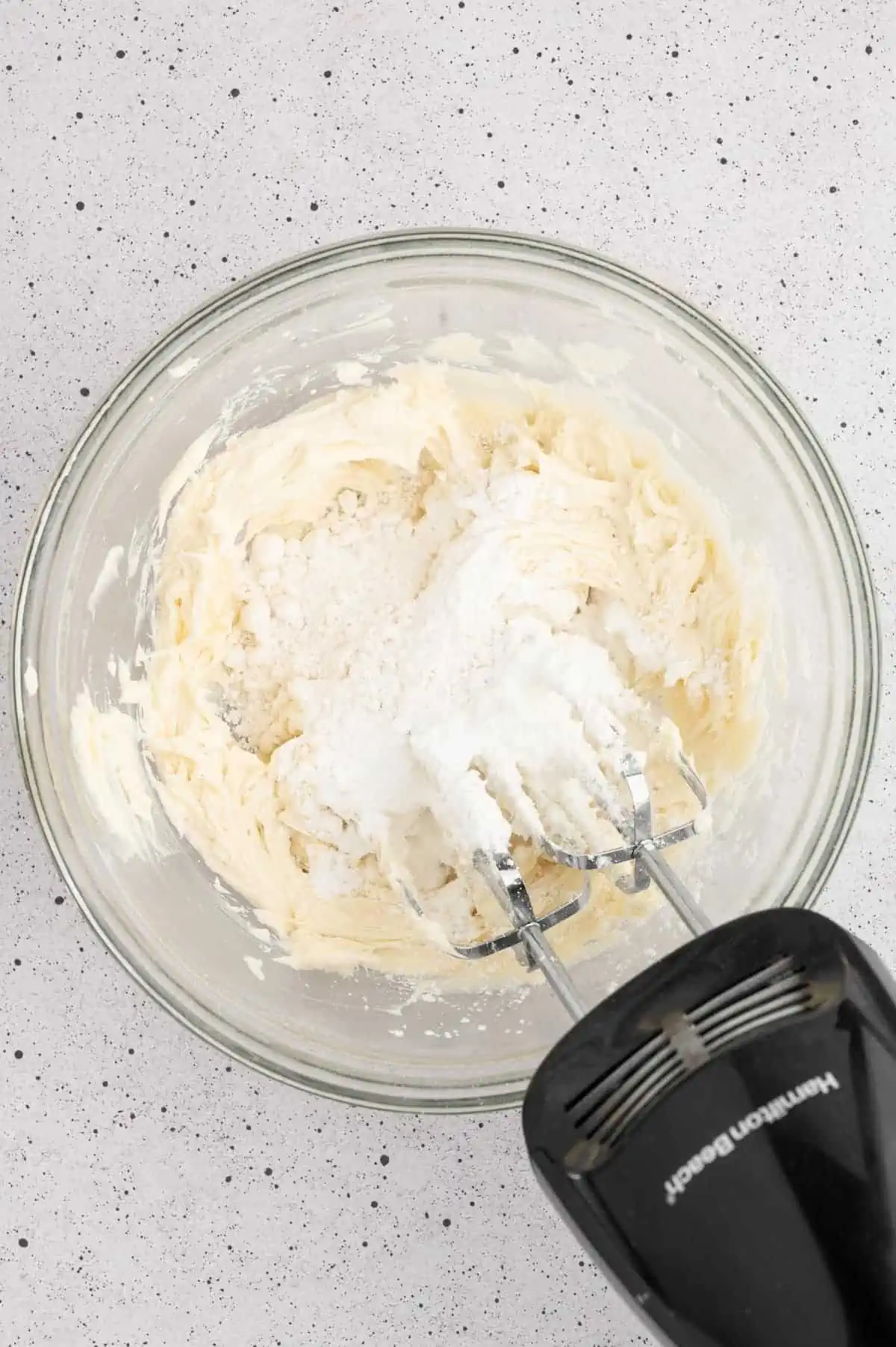 Half cup of powdered sugar added to the top of the creamed vegan butter in a bowl.