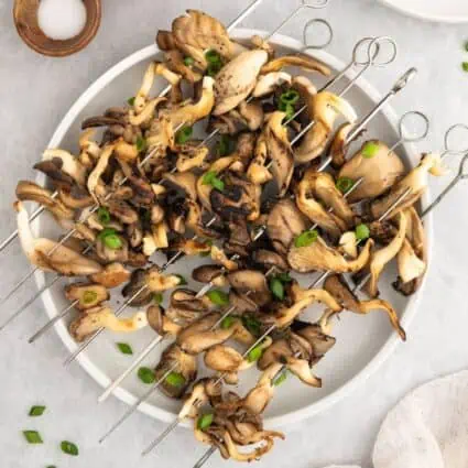 A plate loaded up with grilled mushroom skewers.