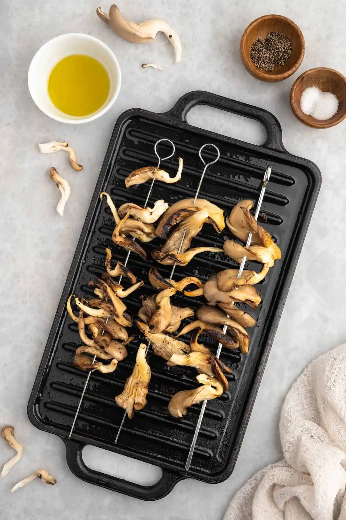 Skewered oyster mushrooms being grilled on a hot grill pan.