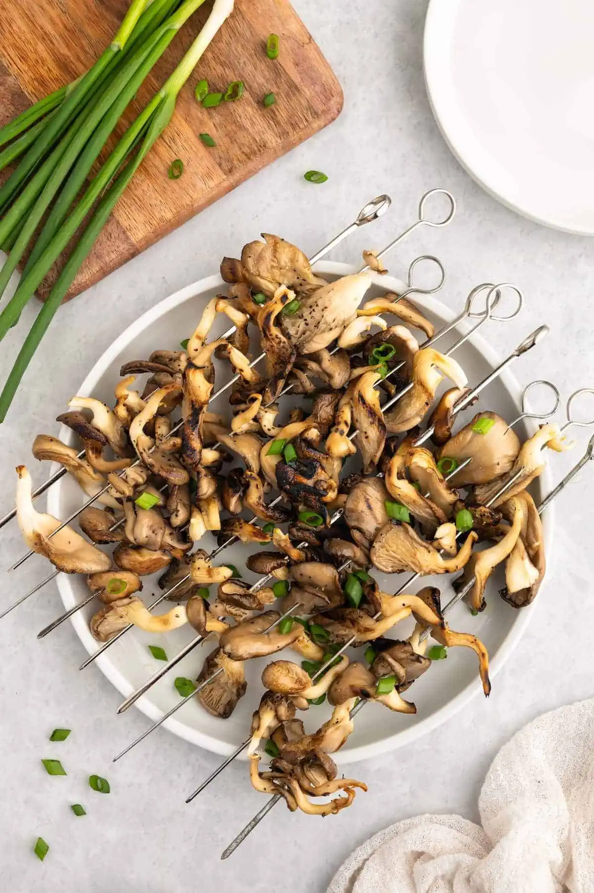 A plate of grilled mushroom skewers with green onions.