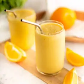 Two glasses of orange juice smoothies, with metal straws.