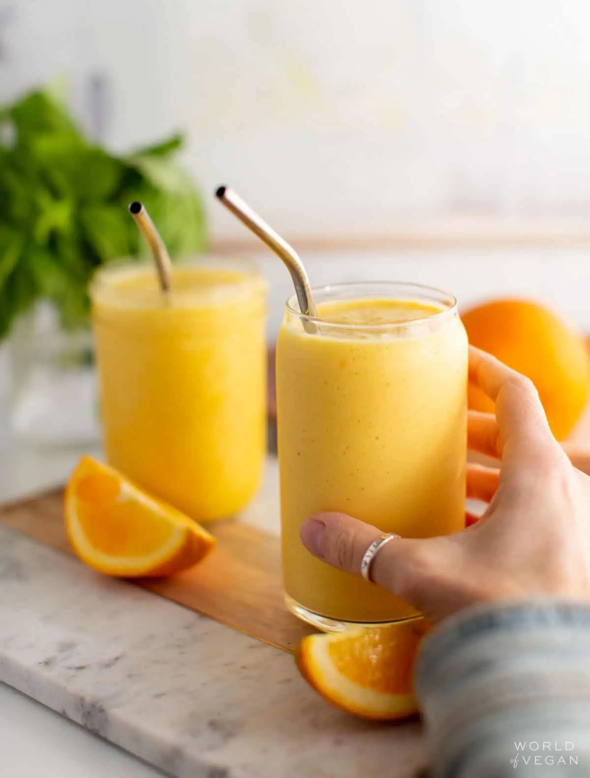 A hand reaching for an orange juice smoothie.