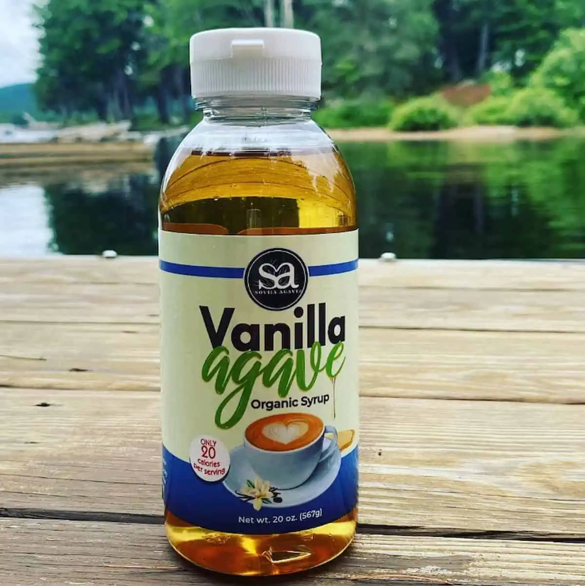 Vanilla agave syrup by Soviia sitting on a wooden dock next to water.