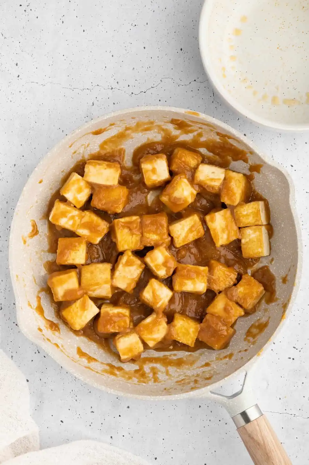 Tofu cubes tossed in Szechuan sauce in a pan.