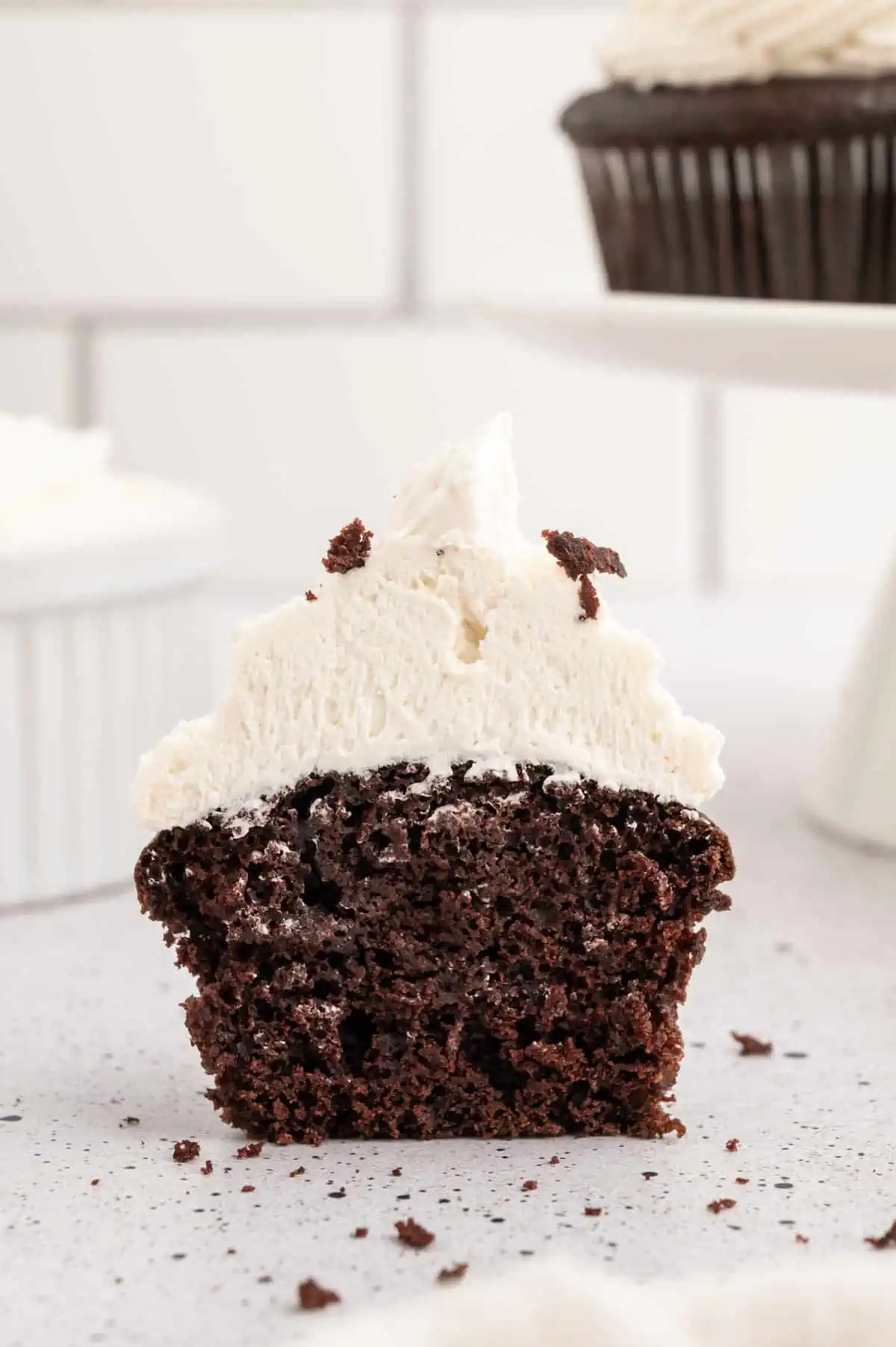 Vegan chocolate cupcake with buttercream frosting sliced in half, showing the inside.