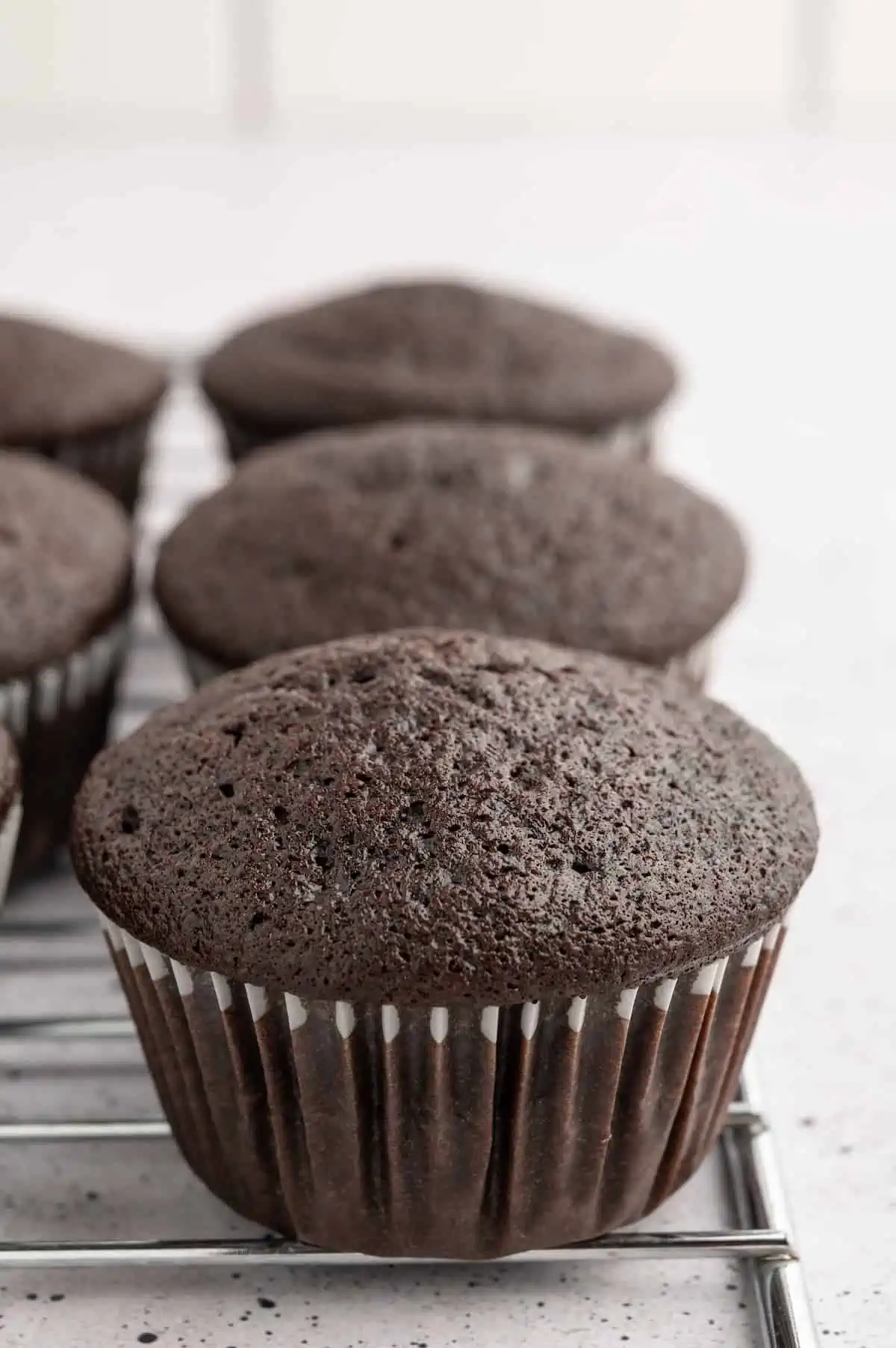 Vegan chocolate cupcakes cooling on a wire rack.