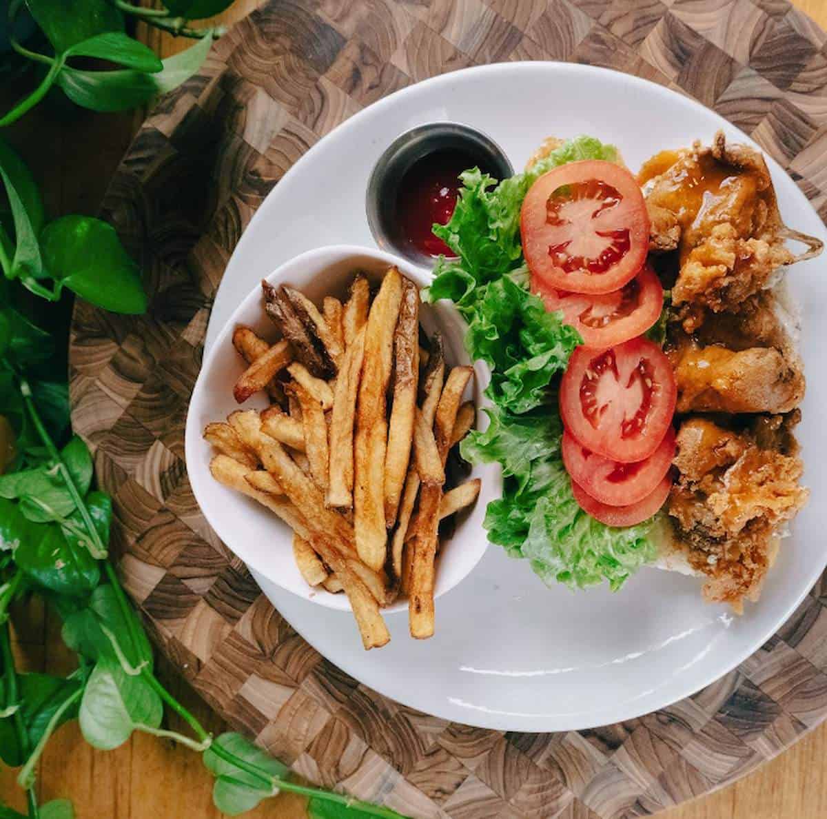 Vegan Oyster Mushroom Po'Boy Sandwich and fries on a plate.