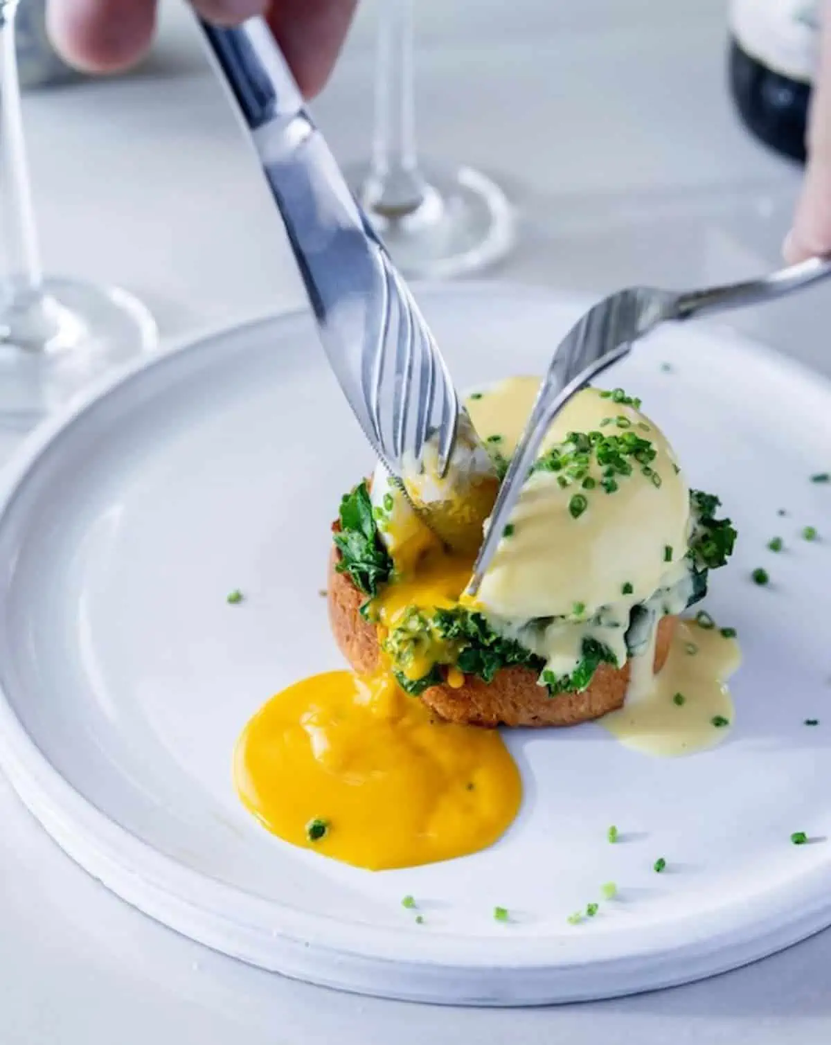 Vegan poached egg with a fork and knife releasing the vegan yolk.