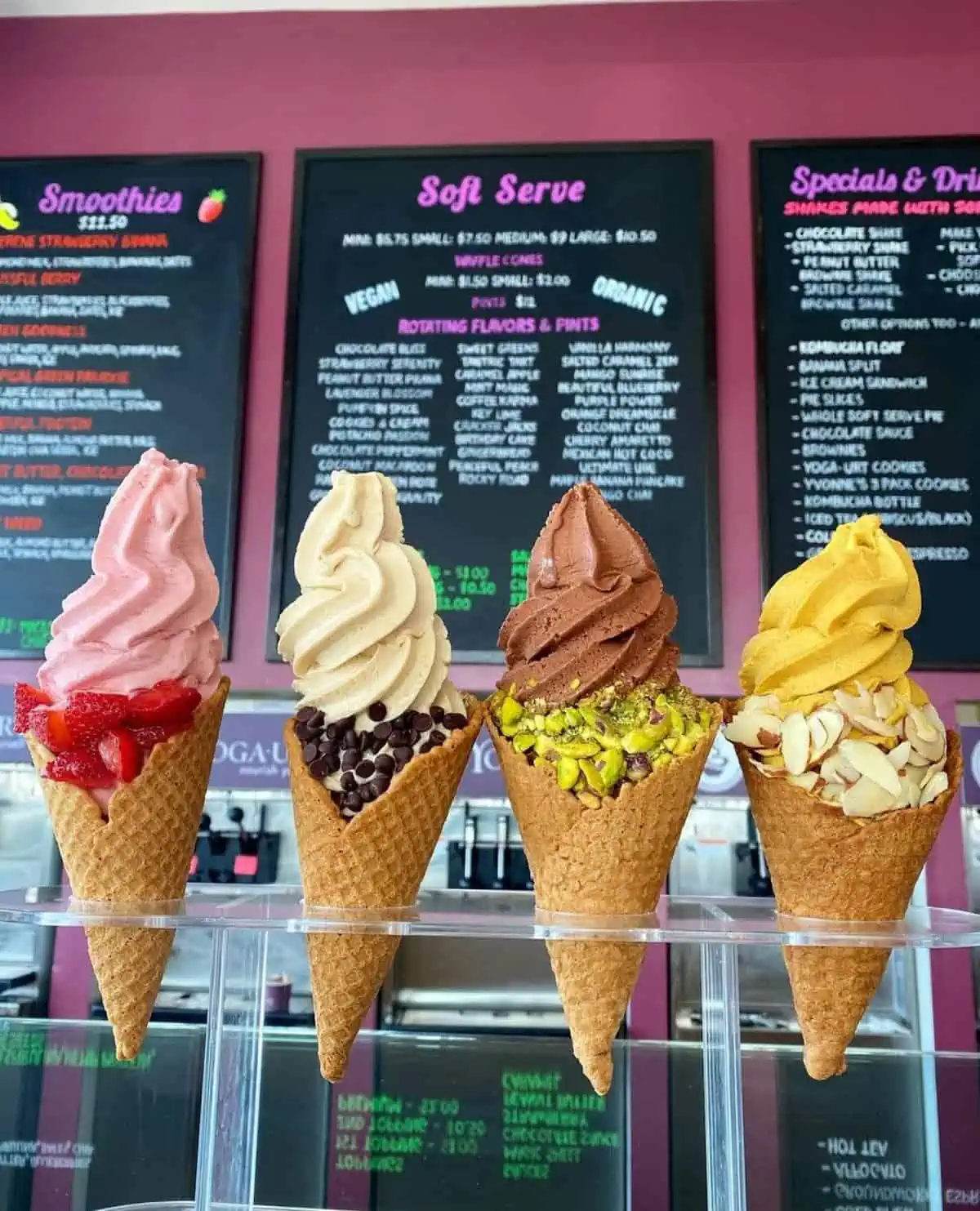 Four vegan yogurt soft serve cones, lined up at a serving counter.