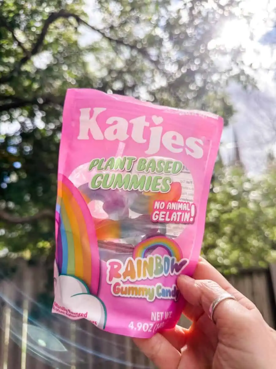 Woman holding up a bag of Katjes rainbow unicorn gelatin-free vegan gummies.