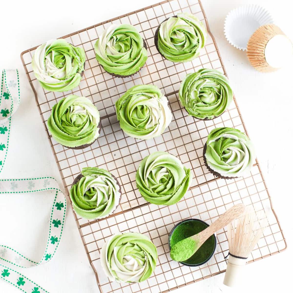 Vegan matcha buttercream cupcakes, arranged on a cooling rack.