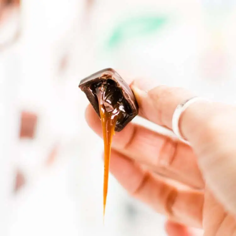 Gooey vegan caramel dripping out of a chocolate dairy free caramel candy.