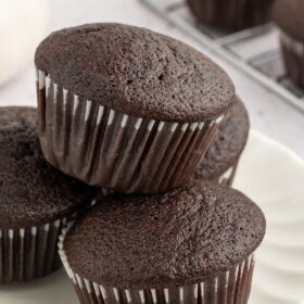 Vegan chocolate cupcakes stacked on a cooling rack.