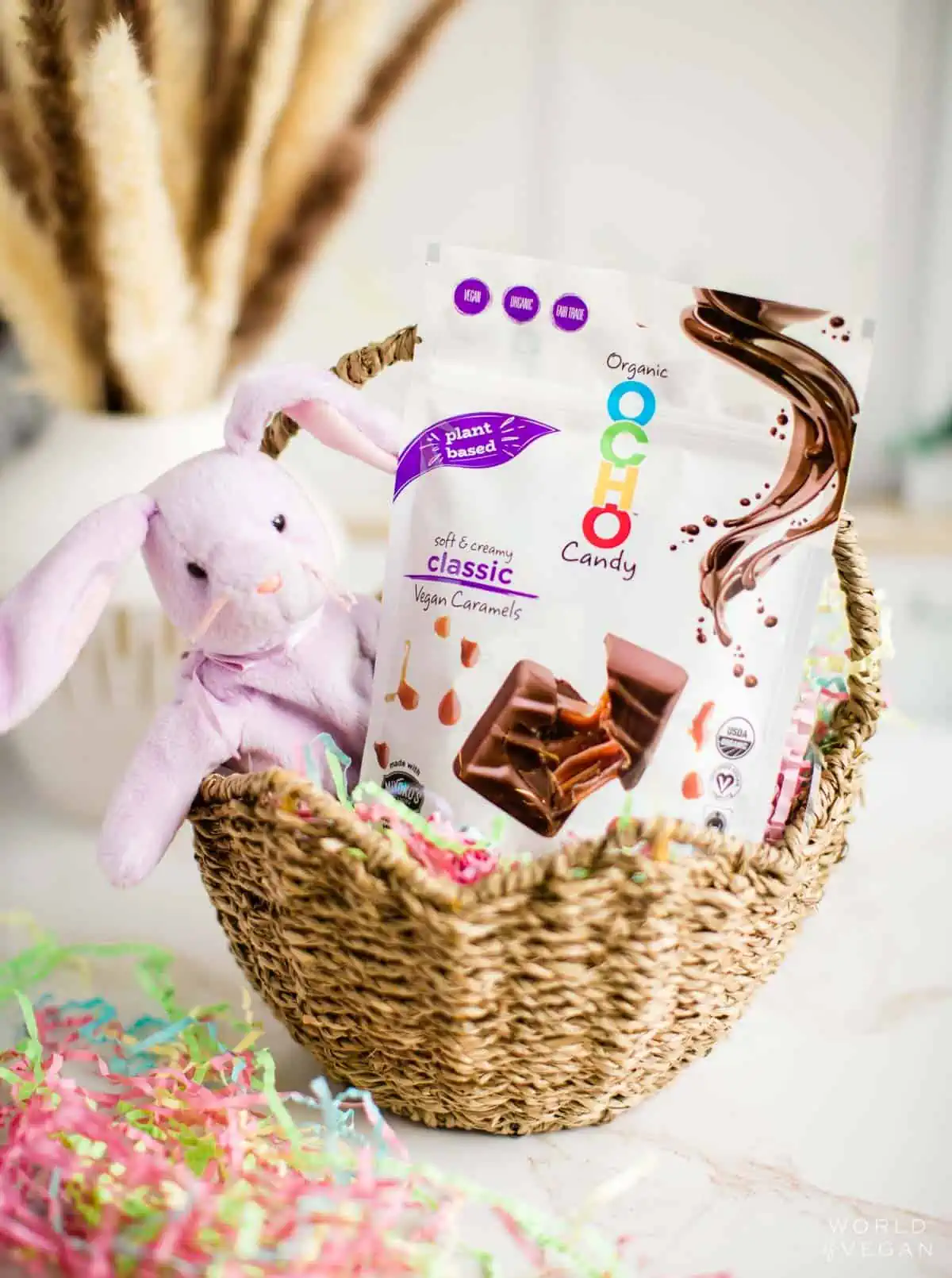 Straw easter basket with a purple stuffed beanie baby bunny and OCHO vegan chocolate caramel candies.