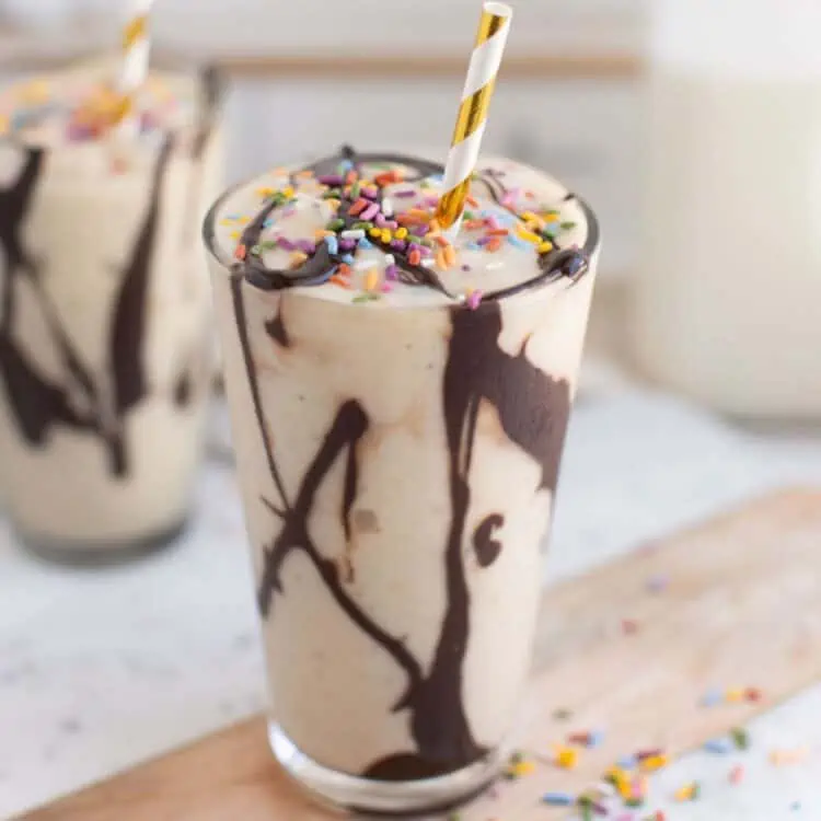 A banana milkshake with a straw on a countertop.