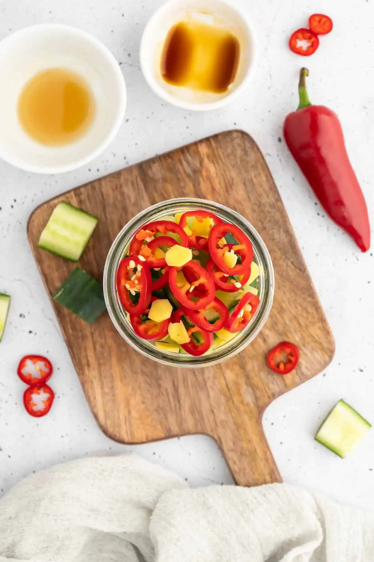 Chilis packed into a jar on a wooden board.