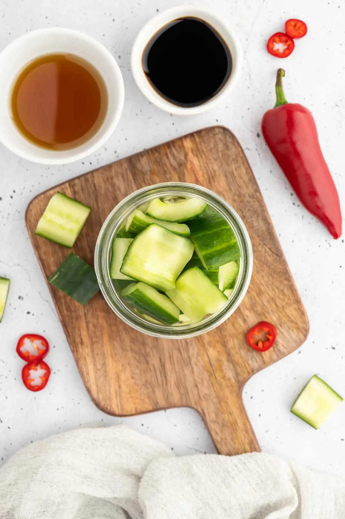 Cucumbers packed into a jar on a wooden board.