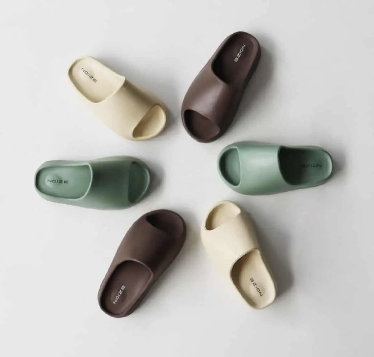 Six pairs of vegan-friendly NOIZE recycled slippers in beige, sage green, and brown arranged in a circle.