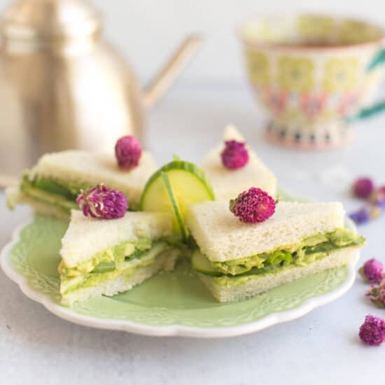 Cucumber avocado vegan tea sandwiches arranged on a plate.