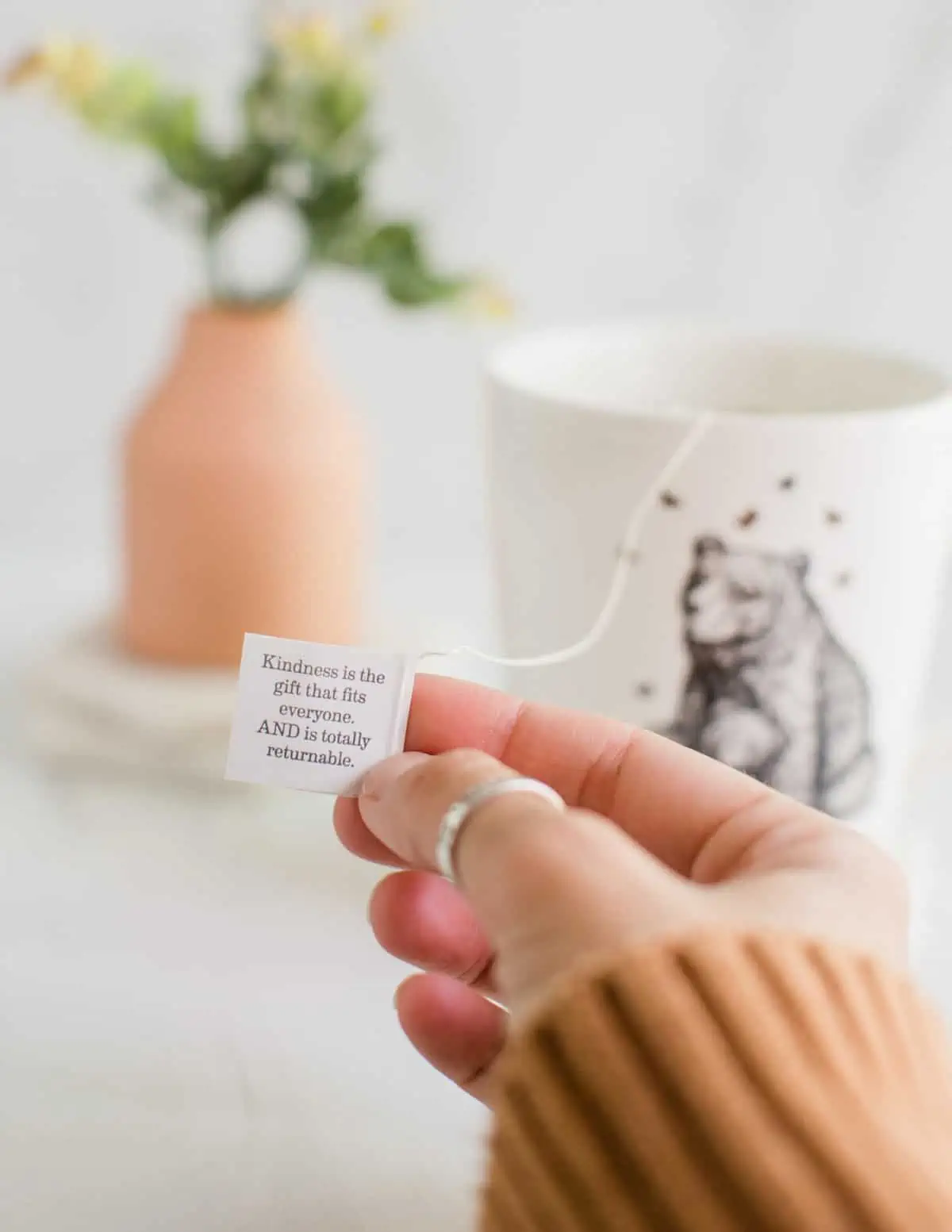 Holding up an Earth Mama vegan tea tag that has an inspiring message about kindness. 
