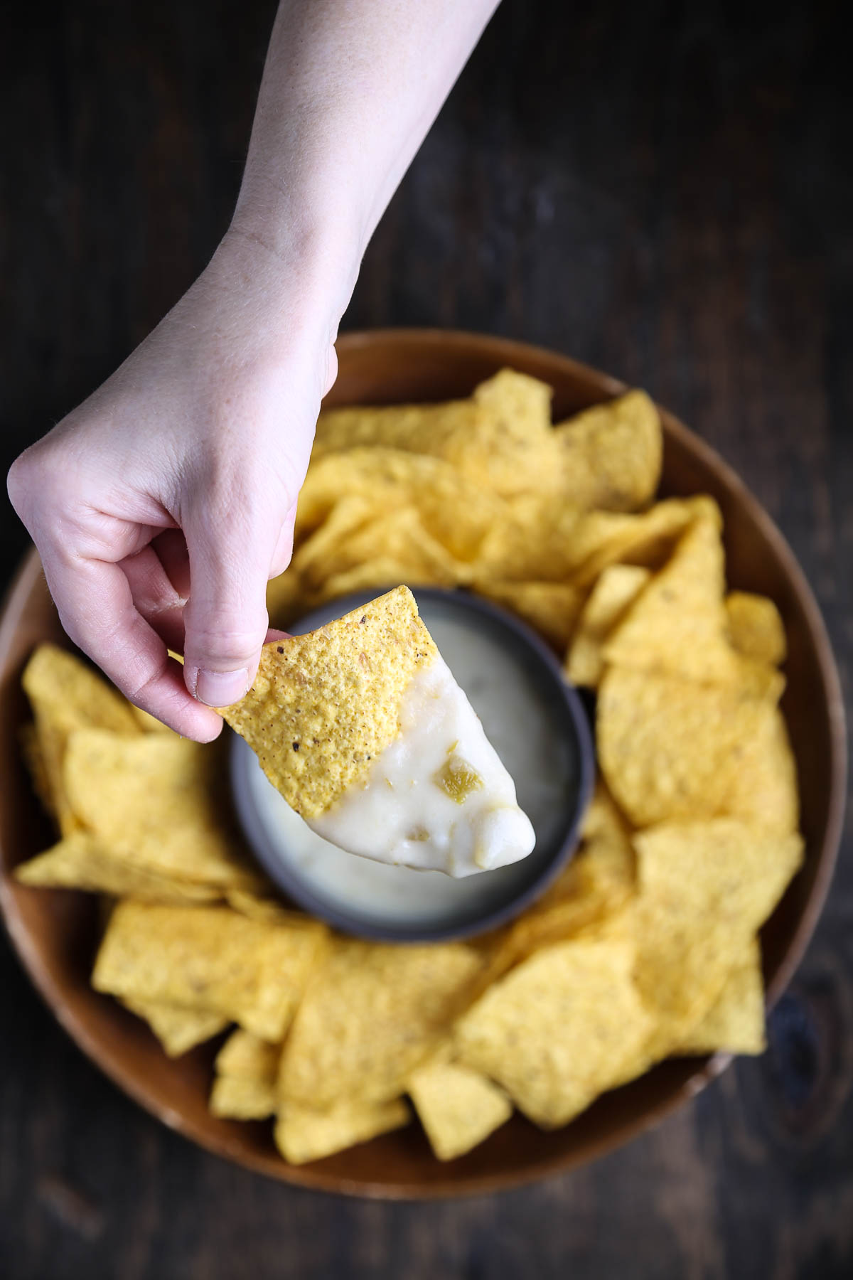 A tortilla chip dipped in vegan queso blanco dip.