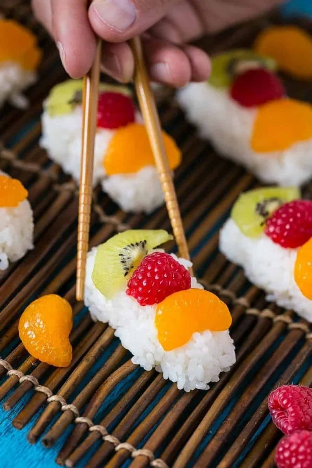 Fresh fruit sushi with chopsticks.