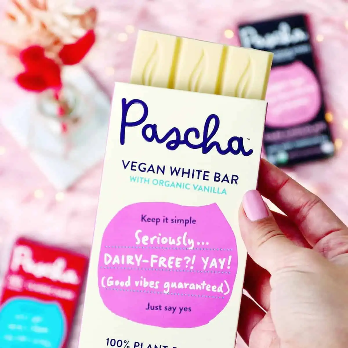 A hand holding a bar of Pascha's vegan white chocolate.